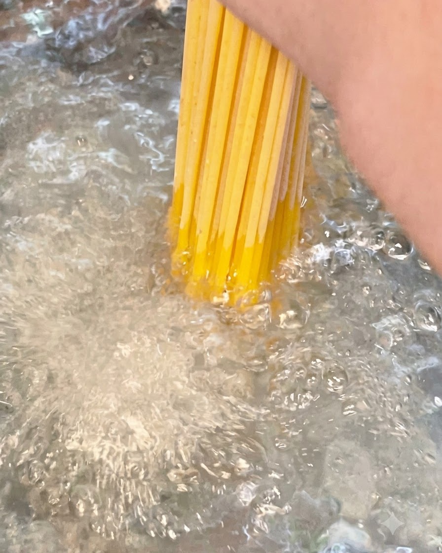 沸騰して塩を加えたたっぷりのお湯に、乾燥スパゲッティの束を入れている様子