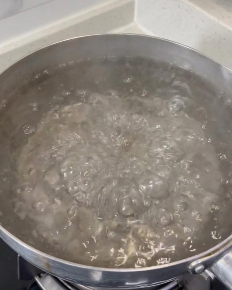 大きな鍋の中で激しく沸騰するお湯に粗塩が溶けていく様子。