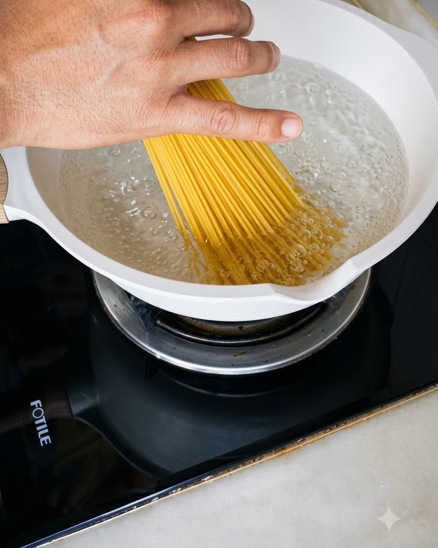 沸騰したお湯がたっぷり入った白い鍋に乾燥スパゲッティを入れている様子。