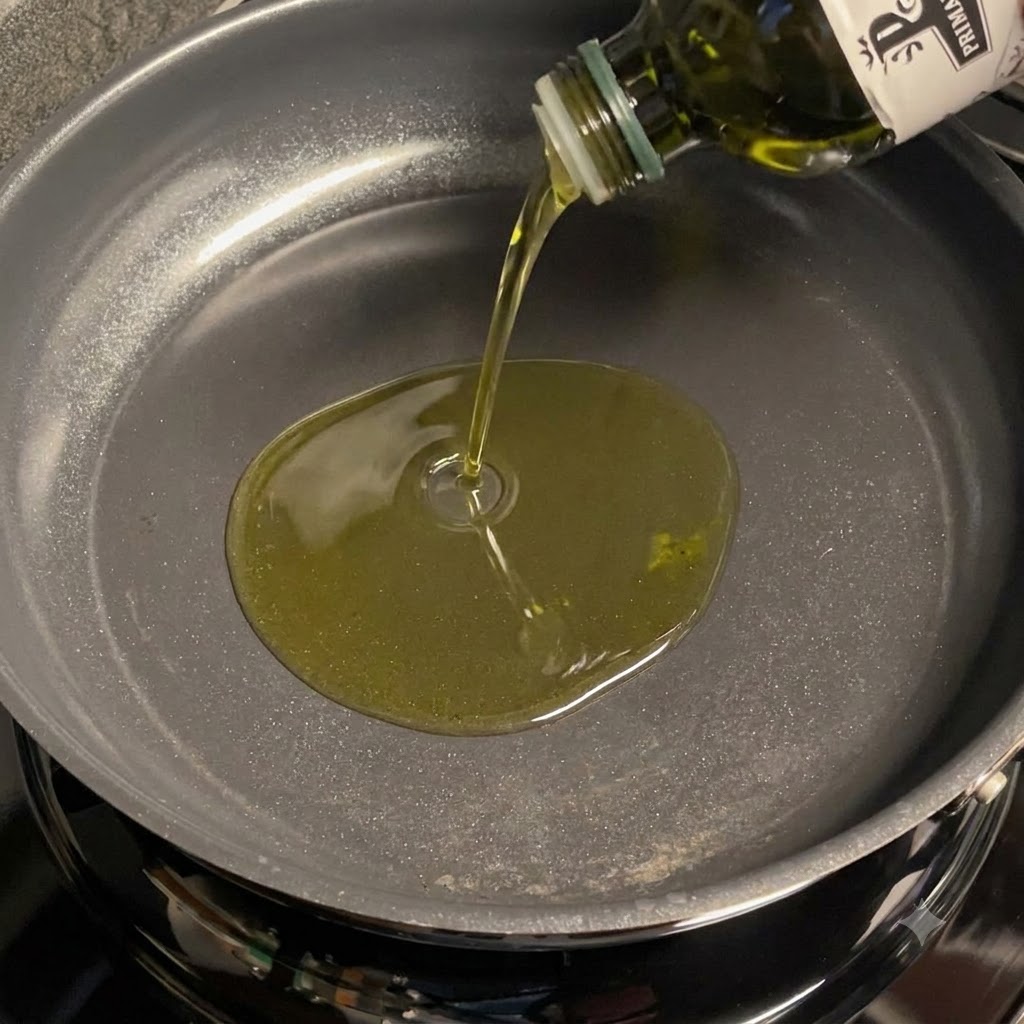 フライパンに注がれたオリーブオイルとスライスニンニク