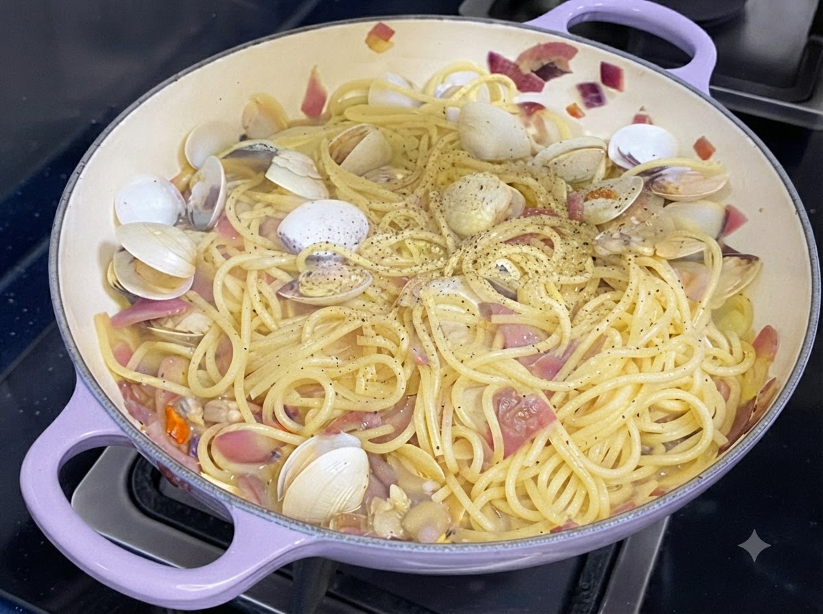調理されたスパゲッティとアサリのフライパンの上に、新鮮な黒こしょうが振りかけられている様子。