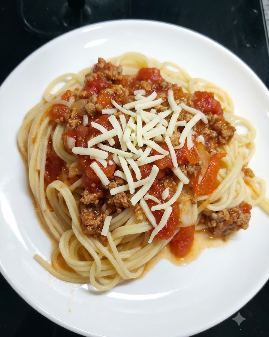 白いお皿に盛られたトマトソースのパスタの上に、シュレッドモッツァレラチーズが散りばめられている様子。