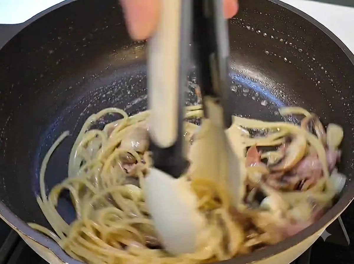 フライパンの中のパスタにバターが加えられ、溶け込んでいるクローズアップ。