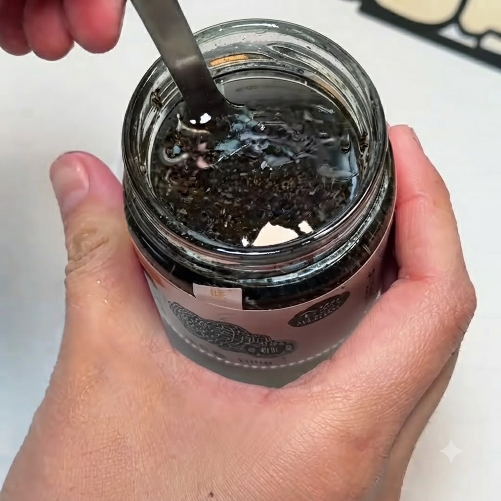 小さなボウルに入った黒トリュフソース、卵黄、塩をスプーンで混ぜ合わせている様子