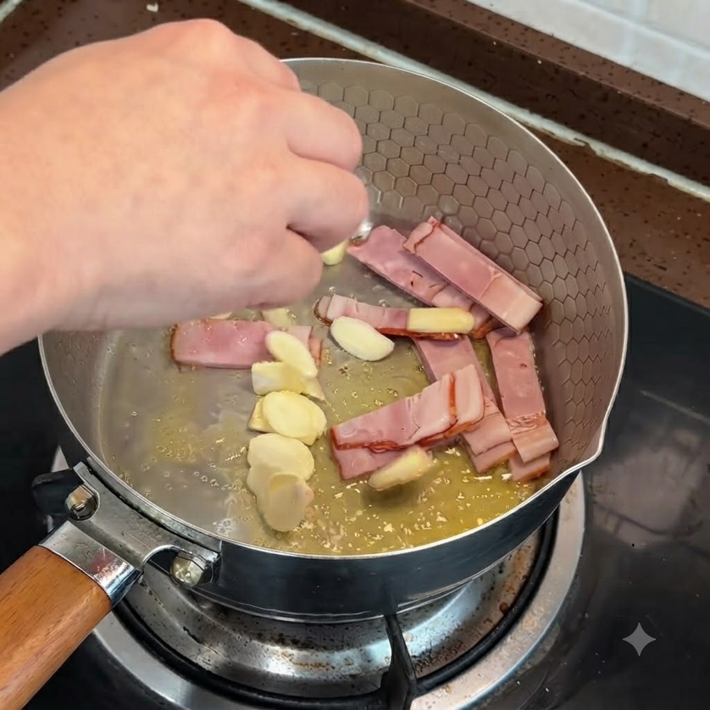 スライスしたベーコンとにんにくを溶かしバターで炒めている様子