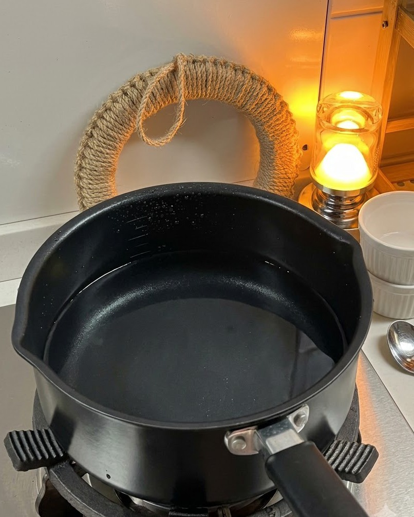 コンロの上の沸騰したお湯の入った鍋に、乾燥したフジッリパスタを入れている様子。