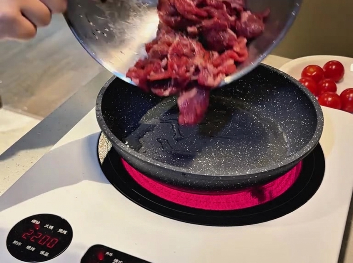 熱したフライパンに下味をつけた牛肉を移している様子。