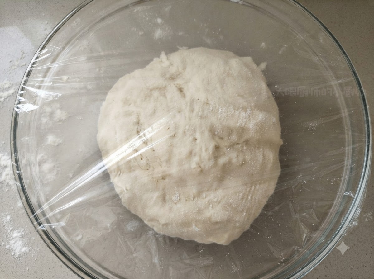 透明なプラスチックラップでしっかりと覆われた透明なガラスボウルの中の滑らかな生地のボール。