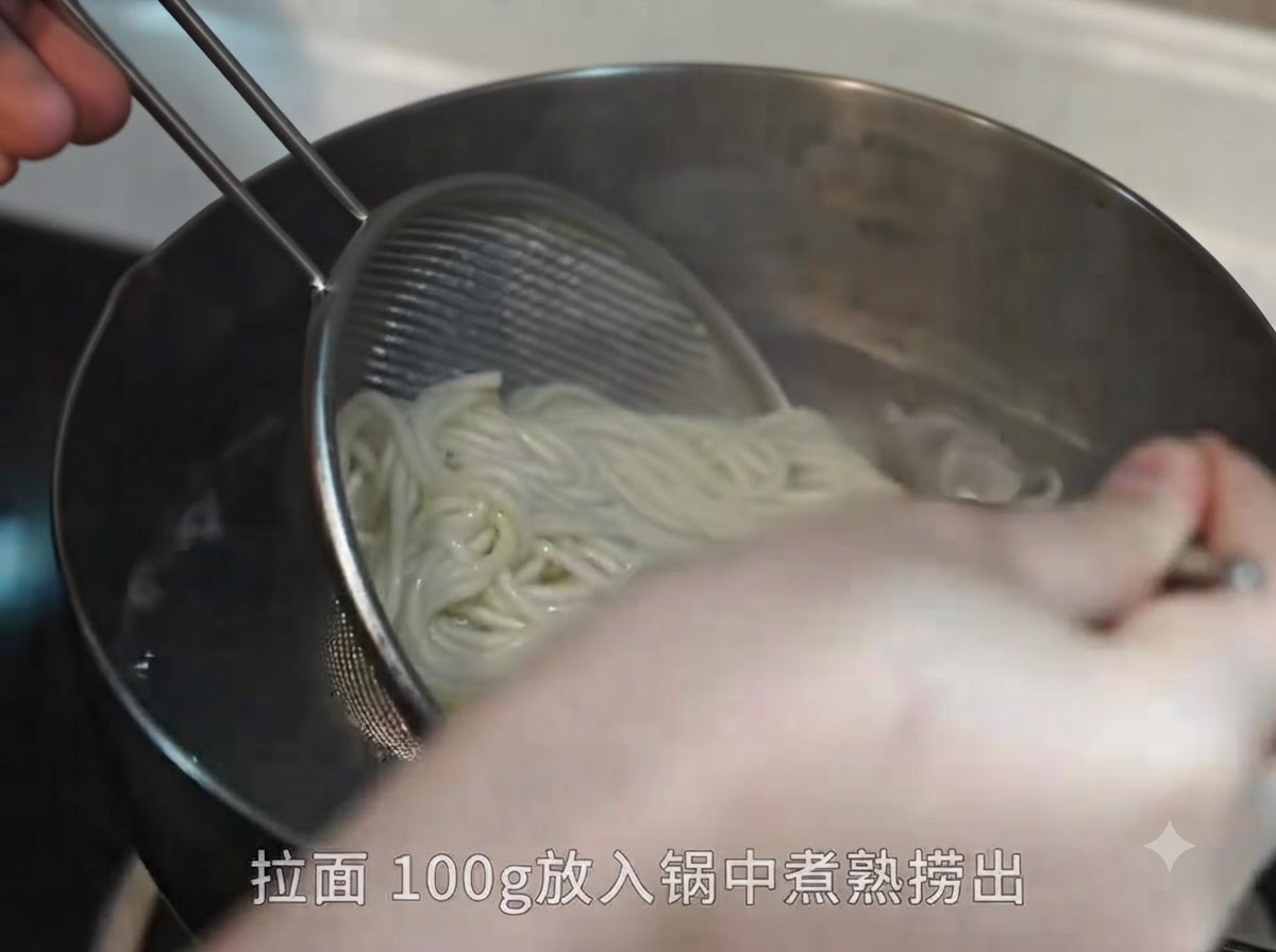 金属製の網ザルと箸を使って、沸騰した鍋から茹で上がったラーメンの麺を引き上げている様子。