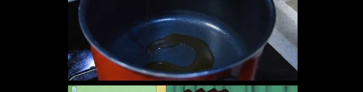 黒い調理鍋の底で薄く引いたごま油が温められている様子。