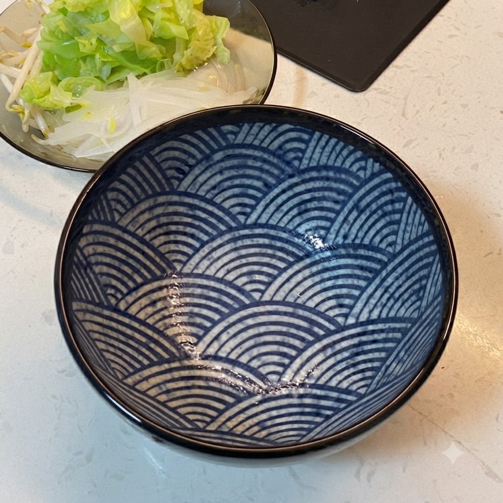 野菜が盛られた皿の隣に置かれた青い模様の食器