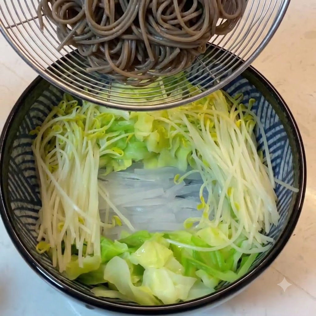 野菜が入った器の上で、ザルに入った茹でたてのそば