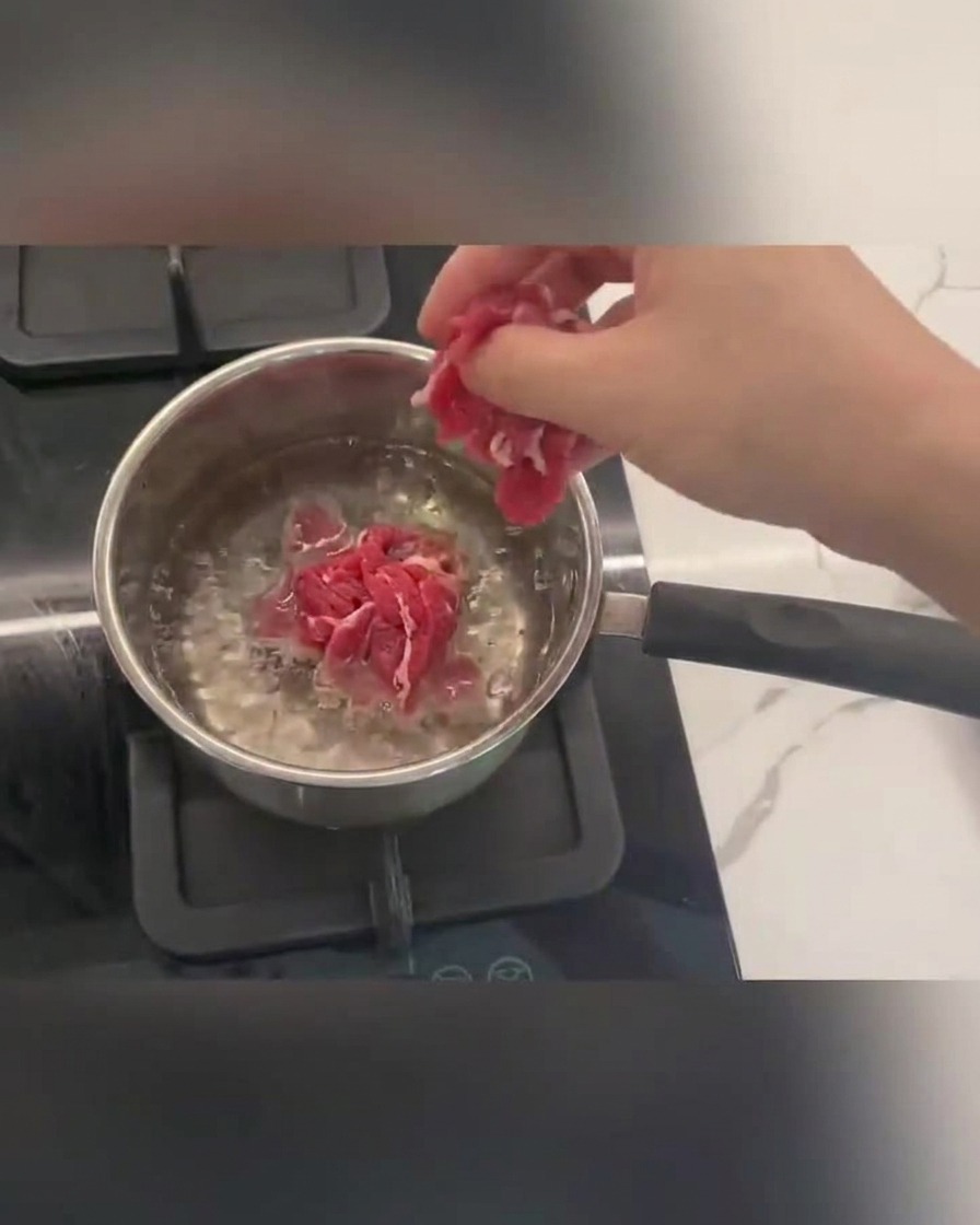 鍋の熱湯の中で泡立ちながら茹でられている牛薄切り肉