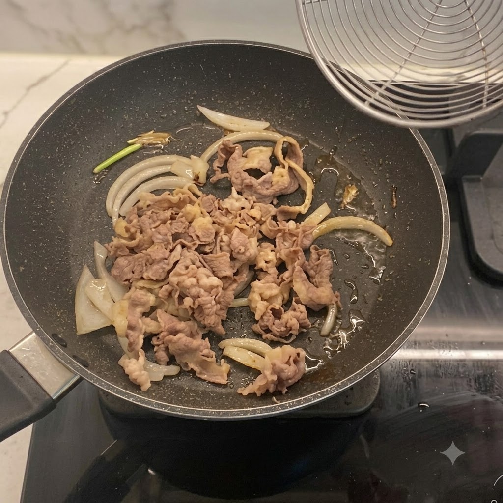 フライパンの中で炒めた玉ねぎと合わされる、下茹でした牛薄切り肉