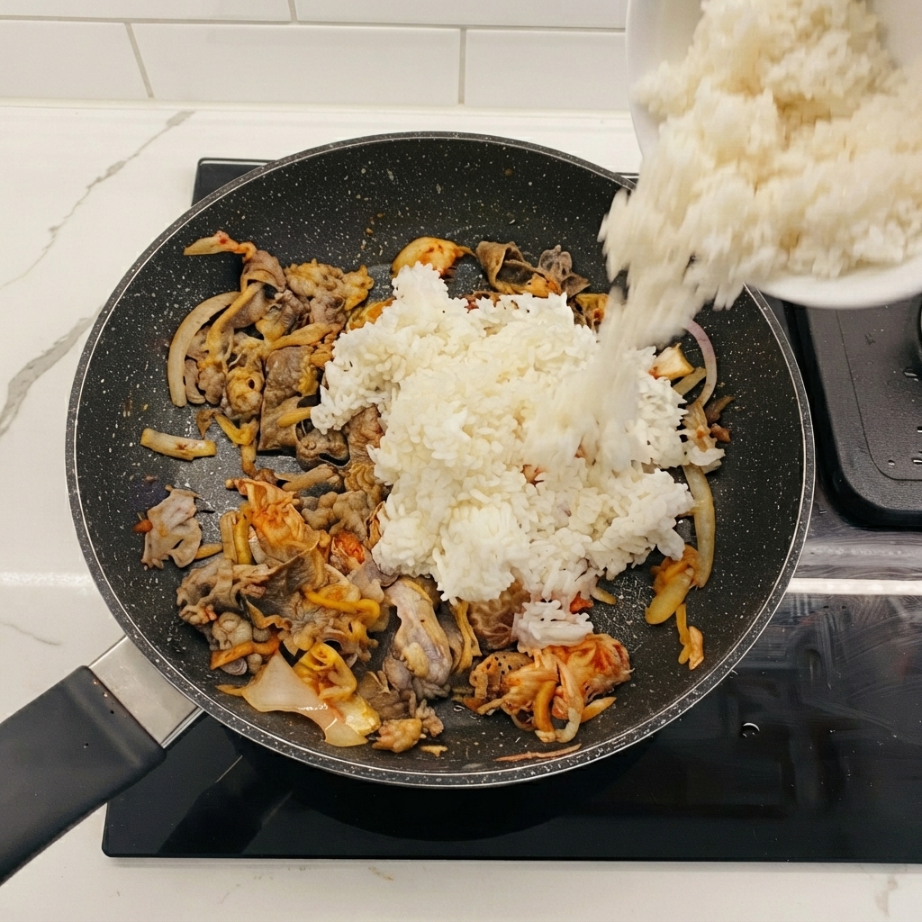 牛肉とキムチが入ったフライパンにボウルから投入される白ご飯