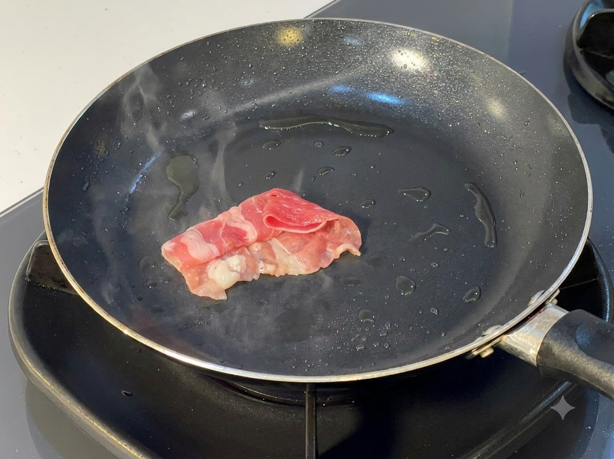 少量の油を引いた熱したフライパンに入れられて焼き目をつけられている、巻いた牛肉のスライス。