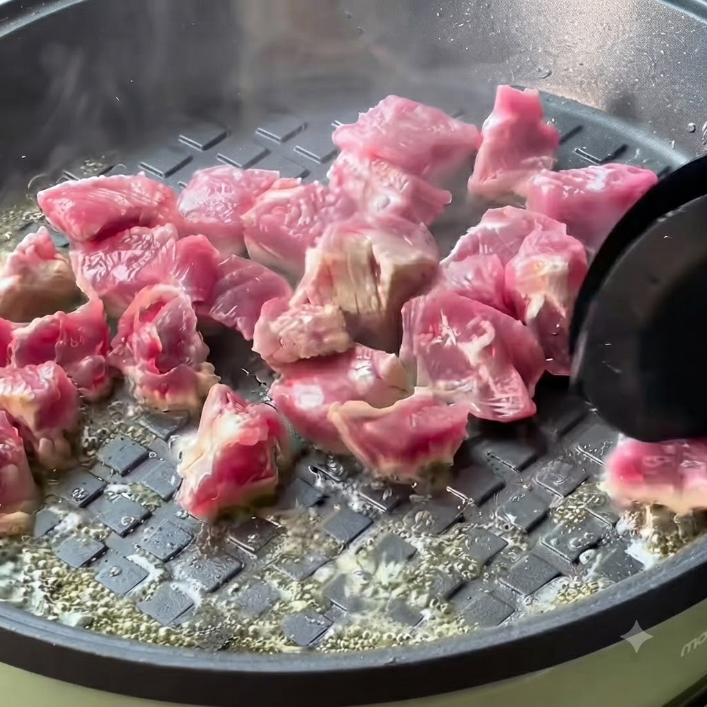 熱したフライパンで調理され、きつね色に焼き色がついていく牛肉の角切り。