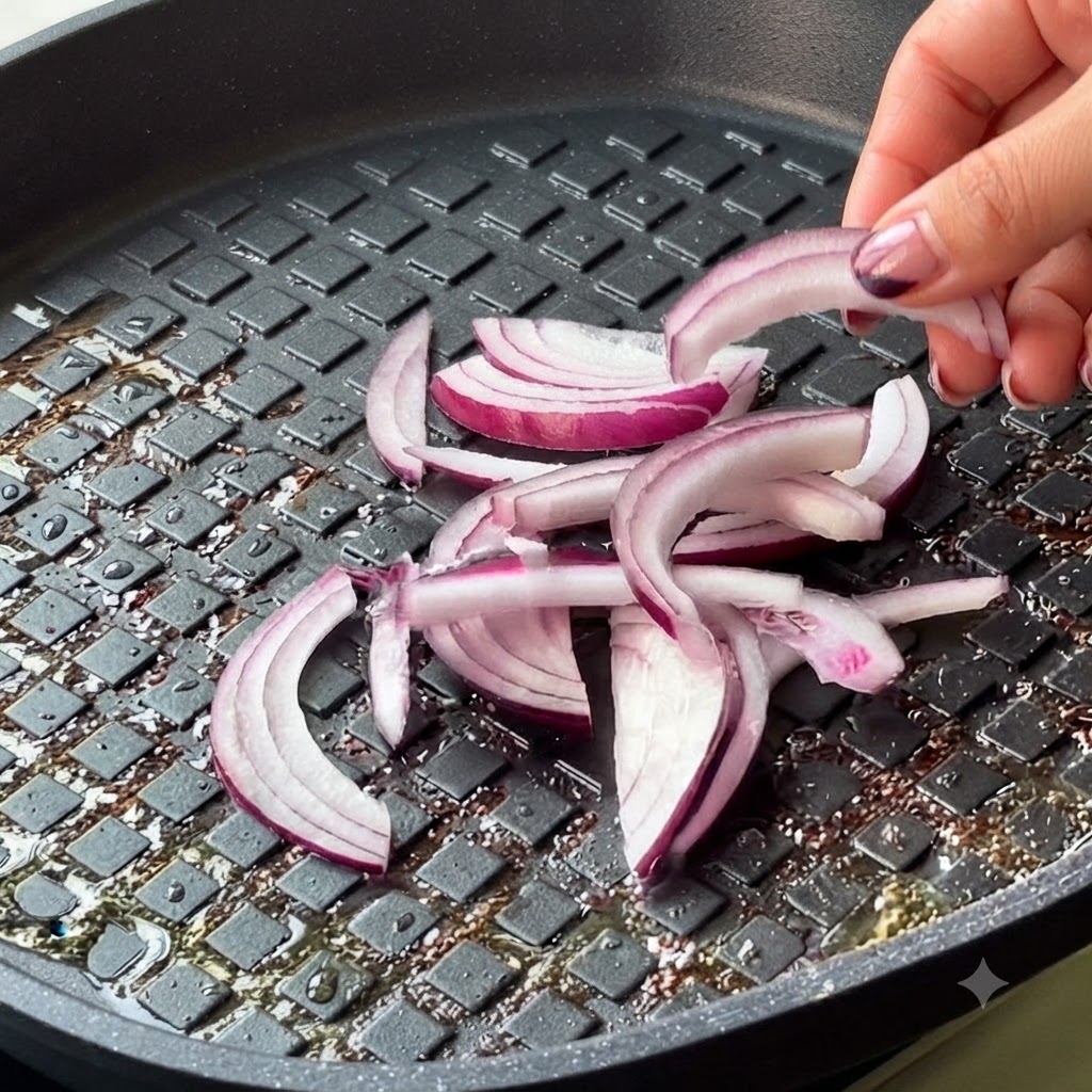 スライスした赤玉ねぎとキムチが、フライパンの中の牛肉に加えられている様子。