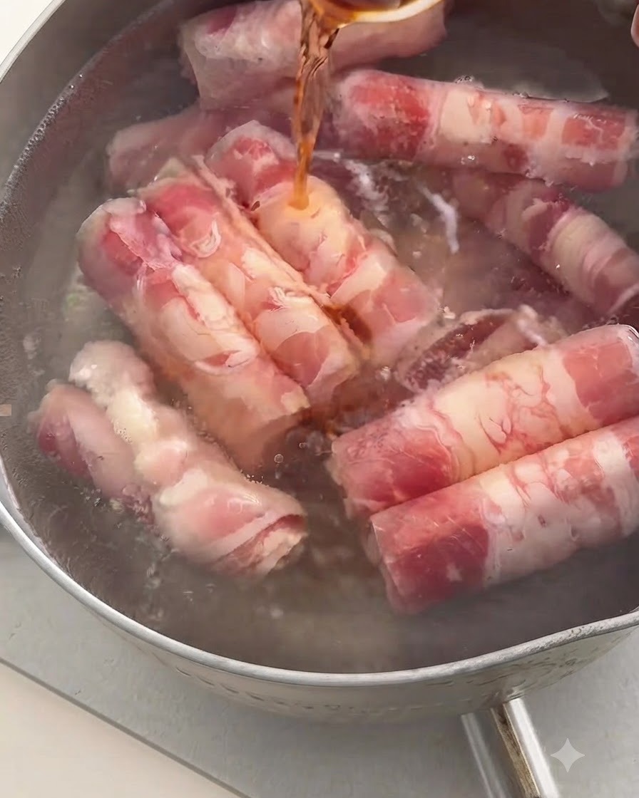 スプーンから濃い色の料理酒を、牛肉ロールが入った沸騰したお湯の鍋に注いでいるところ。