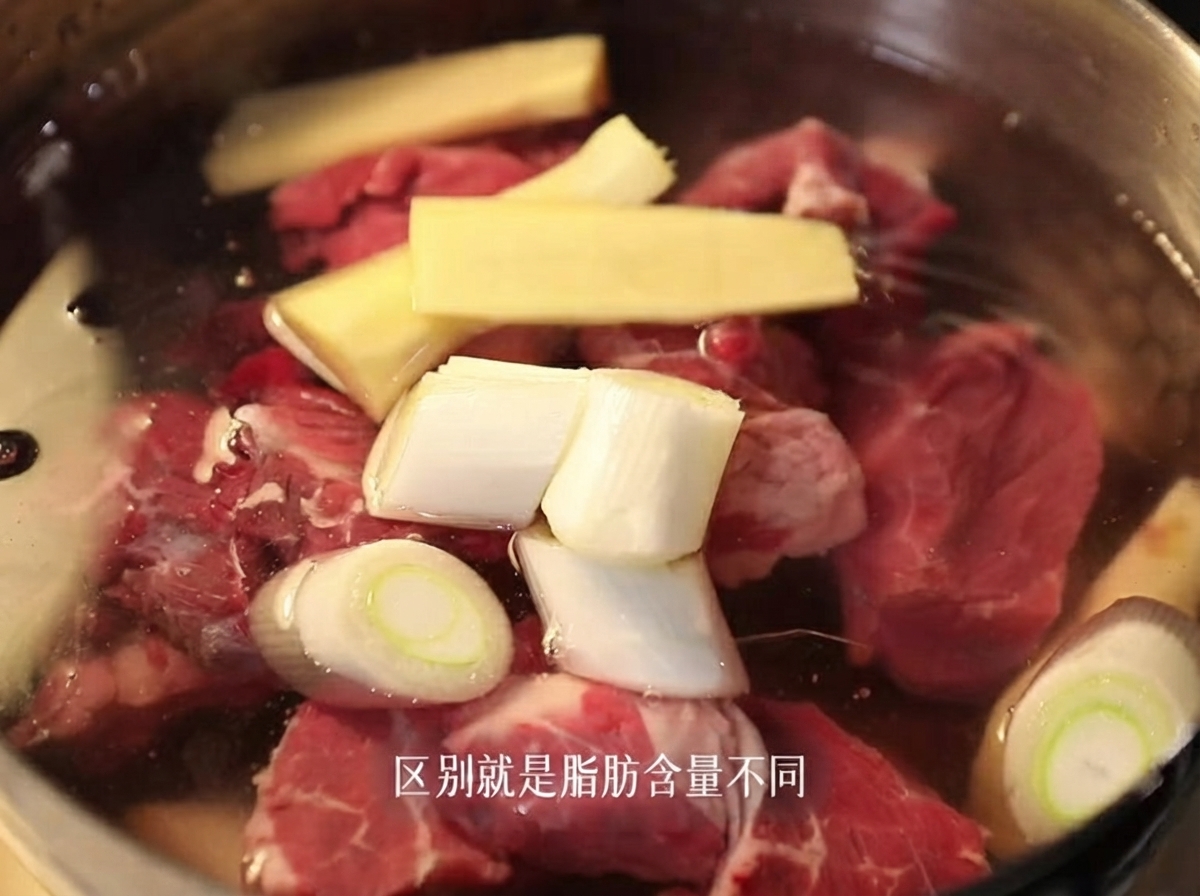 スライスした生姜と長ねぎを入れた冷水の鍋に、生の牛バラ肉の塊が入っている様子