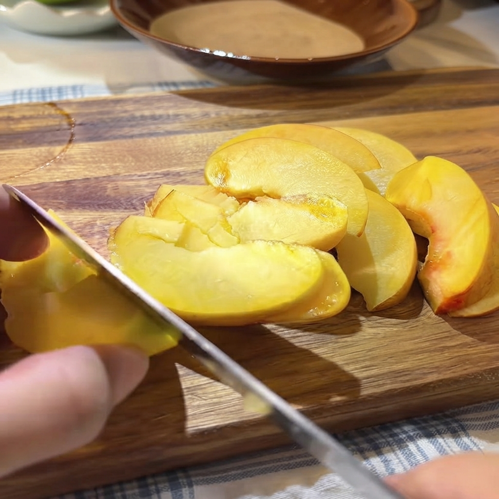 まな板の上にスライスした黄桃の上に、フレッシュなパッションフルーツの種と果肉をスプーンですくい入れているところ。