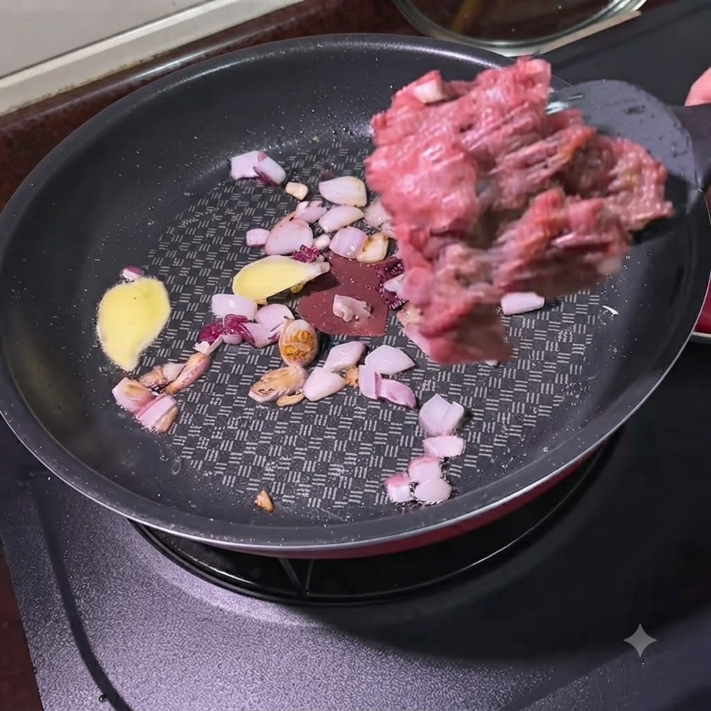 炒めた玉ねぎと生姜が入ったフライパンに、スパチュラを使って牛挽き肉を加えているところ。