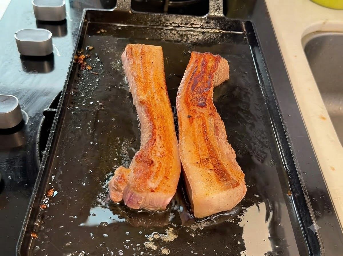 グリルパンの上で、厚切りの豚バラ肉がキッチンバサミで小さく切られている様子。