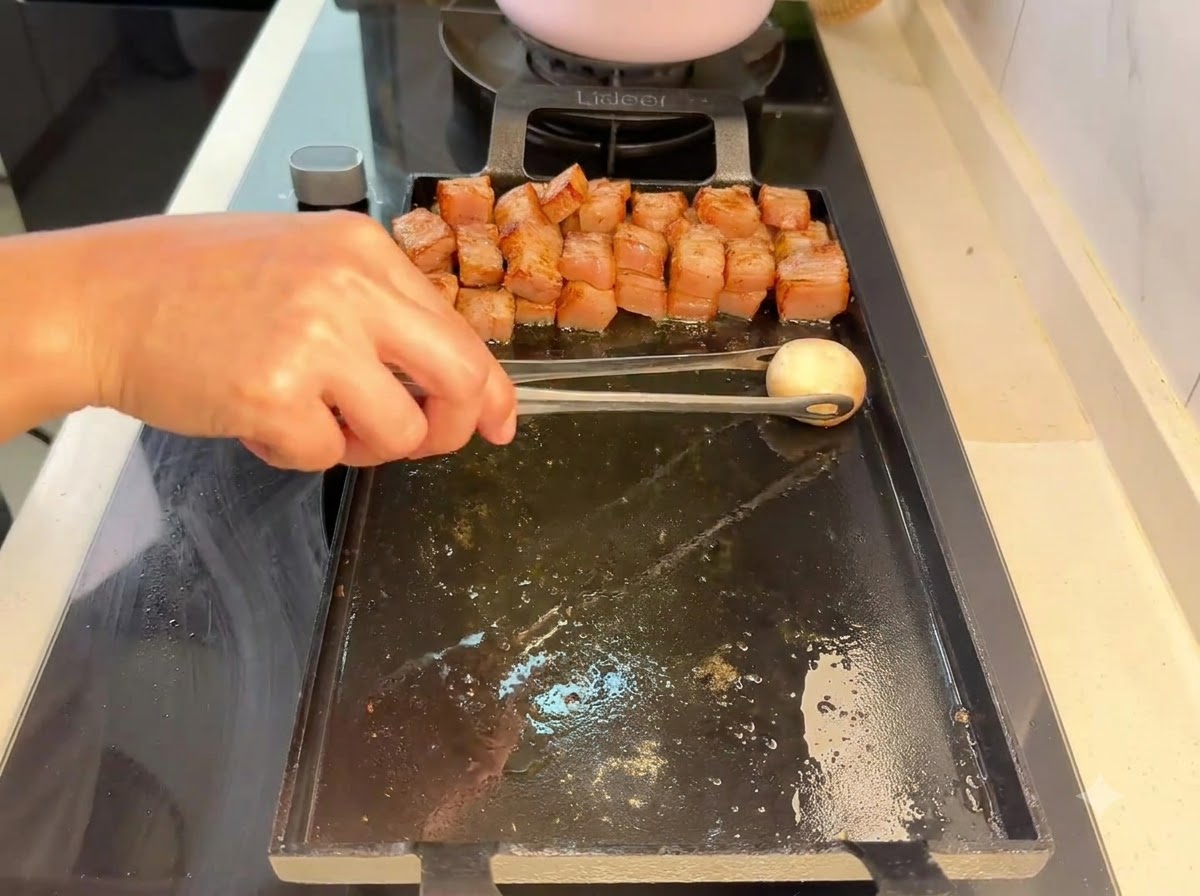 トングを使って、焼いた豚肉の隣にマッシュルームをグリルに置いている様子。