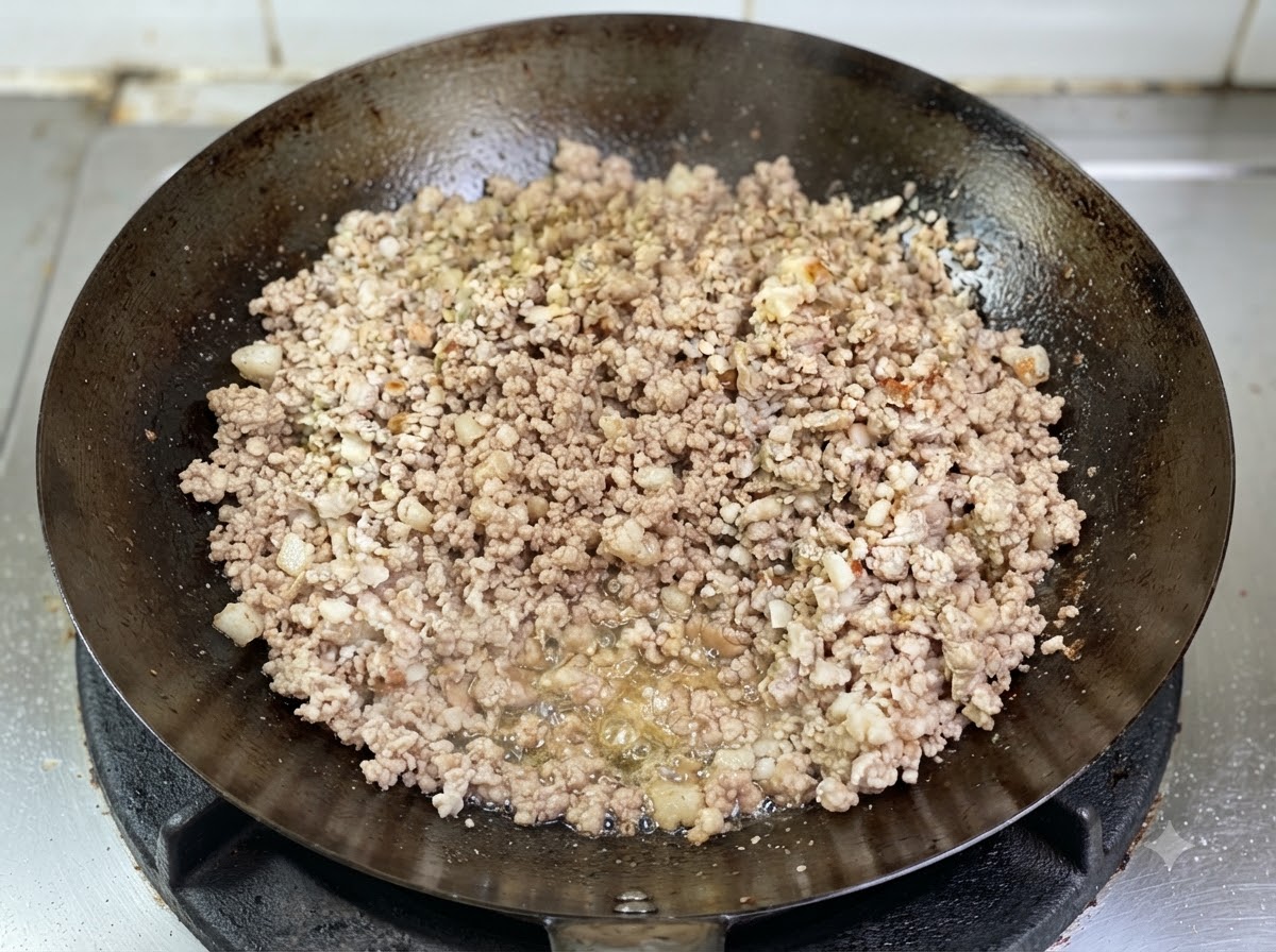 中華鍋の中でひき肉が炒められ、底の方に溶け出した透明な油が泡立っているところ。