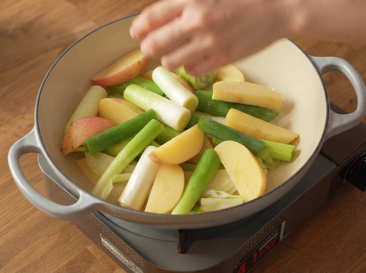調理鍋の中の野菜層の上に、下味をつけた生の豚バラ肉がしっかりと置かれている様子。