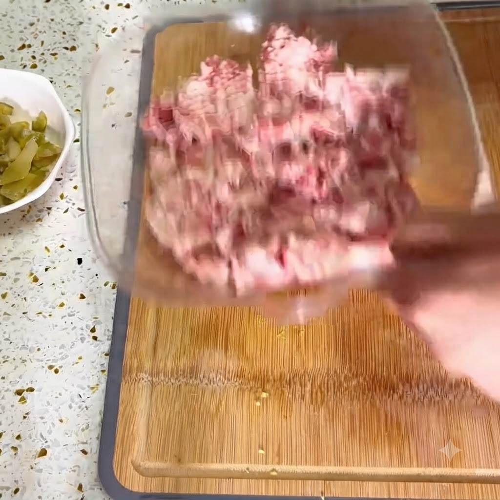 木製のまな板に置かれたひき肉のボウルに、みじん切りにした生姜を入れている様子