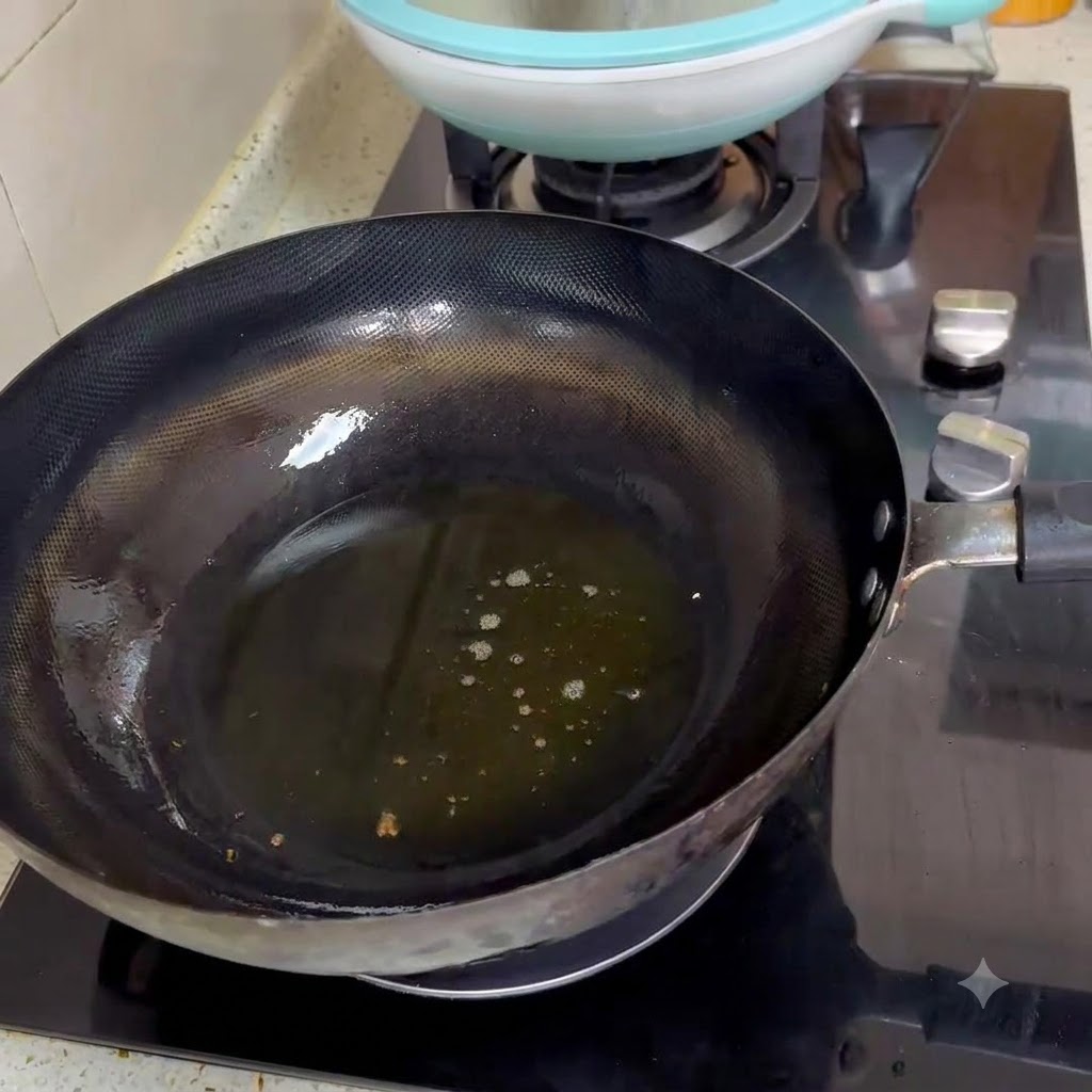黒い中華鍋の熱した油の中で、2杯の豆板醤を炒めている様子
