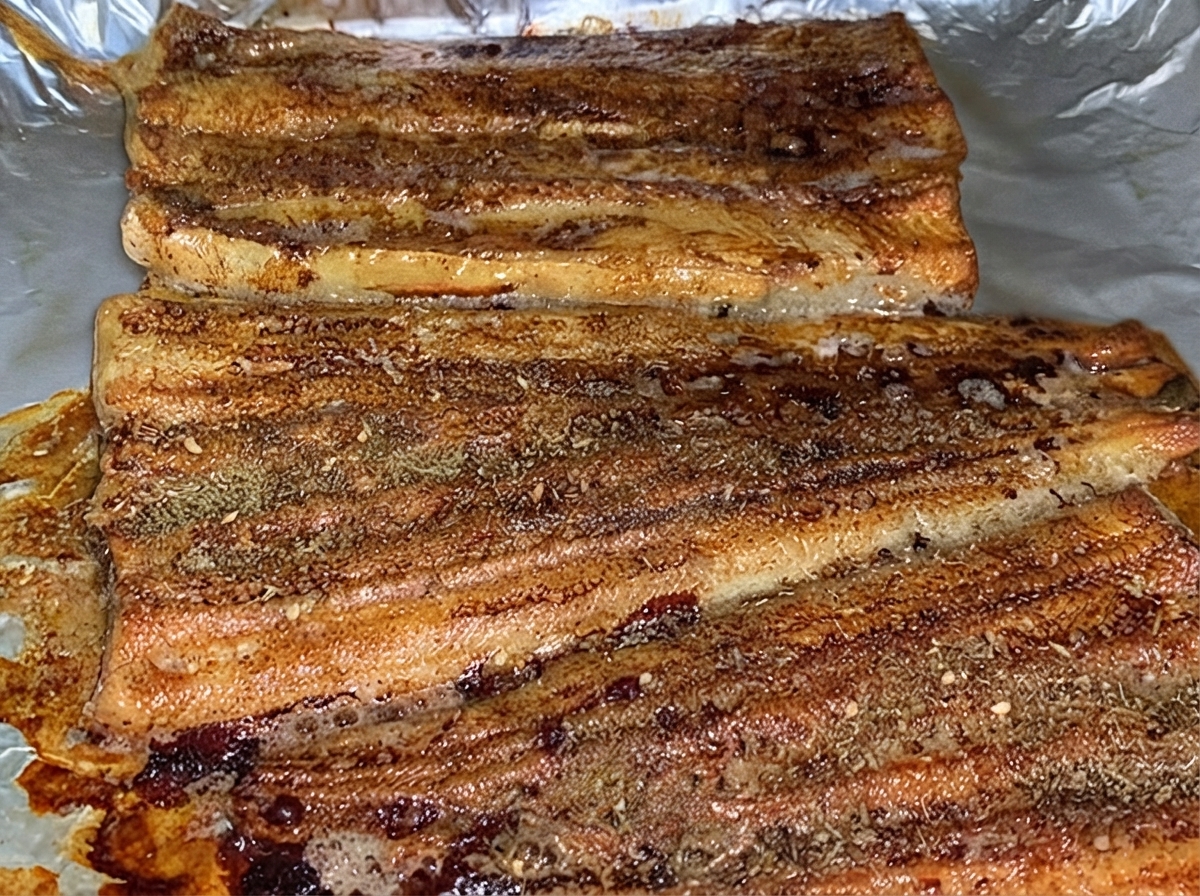オーブン皿の中のタレを塗ったうなぎの焼き身に、茶色のBBQスパイスパウダーが均等に振られている様子。