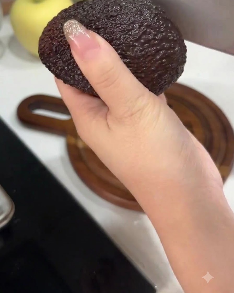 大きめの包丁を使ってアボカドを半分に切り分けている手。