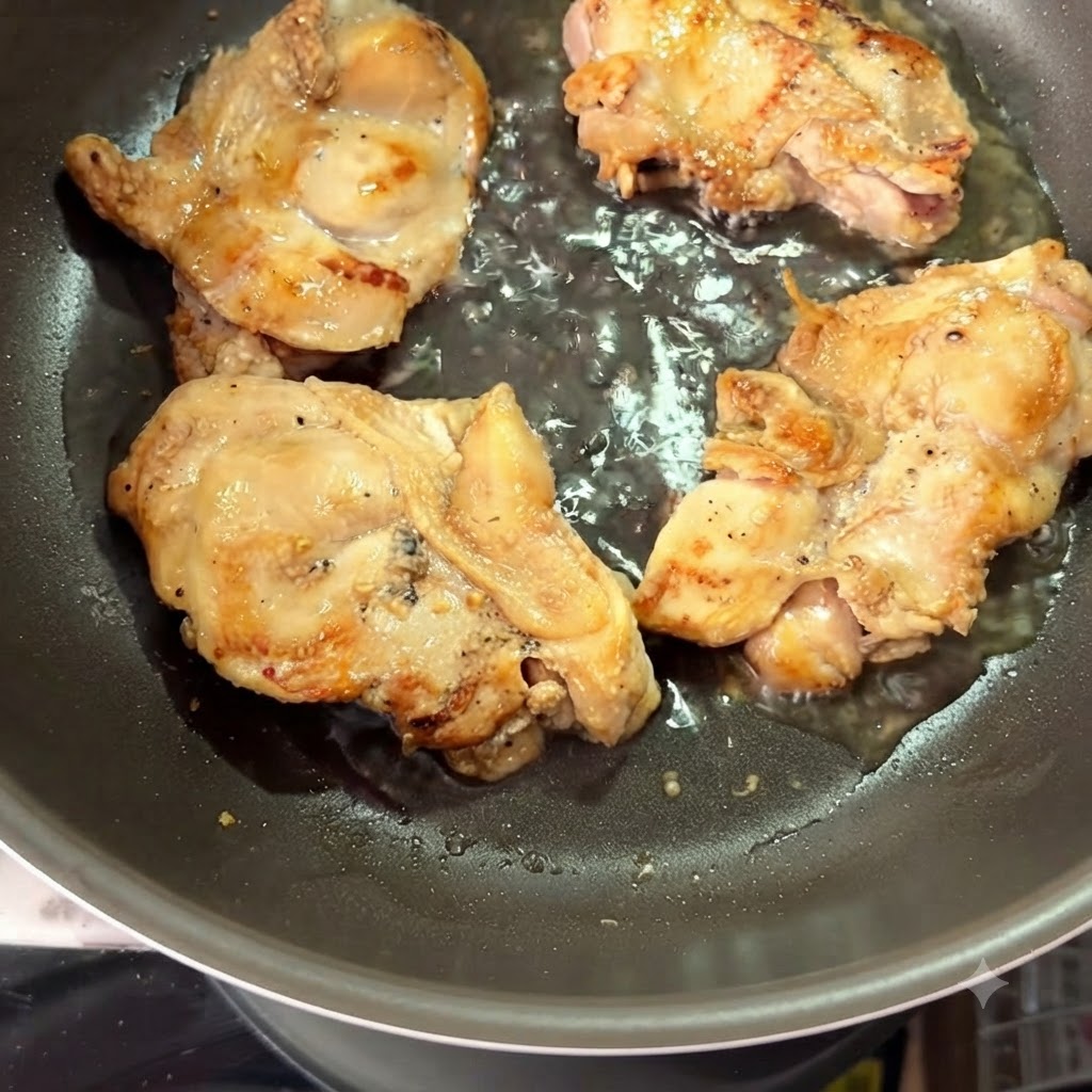 焼き色がついた鶏もも肉の周りに熱湯が注がれているフライパン。
