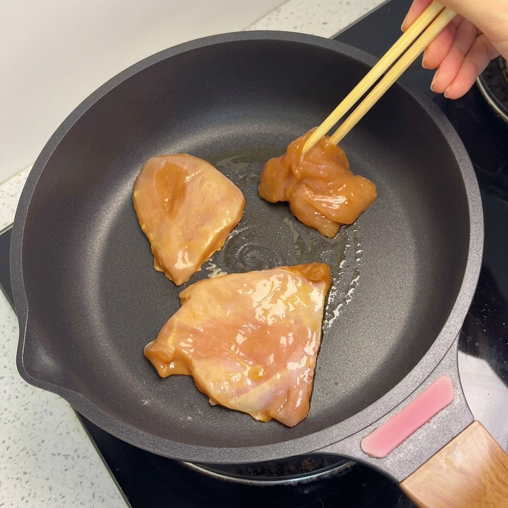 フライパンで香ばしいきつね色に調理されている鶏むね肉のピース。