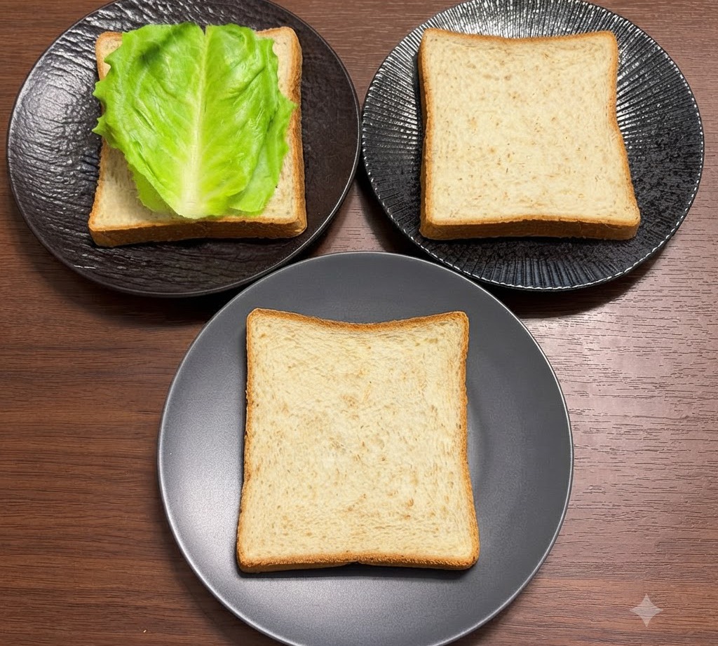黒い皿に置かれた全粒粉パンの上に、新鮮な緑色のレタスの葉がきれいに並べられている様子。
