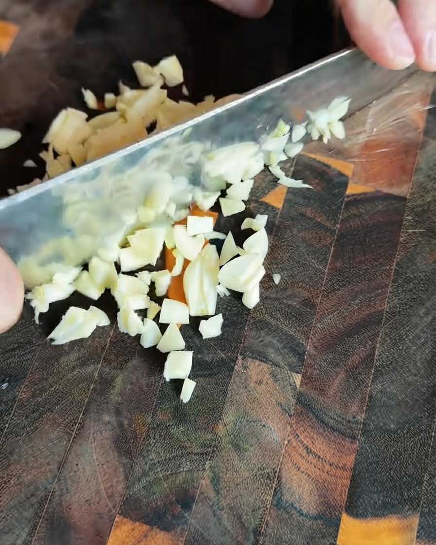 濃い色のまな板の上に散らばった細かくみじん切りにされたニンニク
