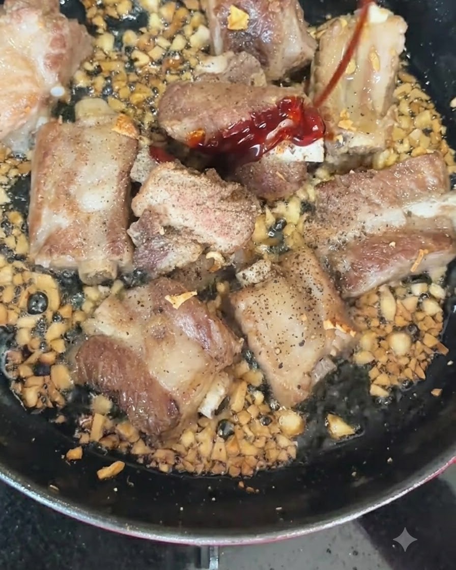 香ばしく焼けているスペアリブと刻みニンニクが入った熱いフライパンに投入される赤と緑の唐辛子