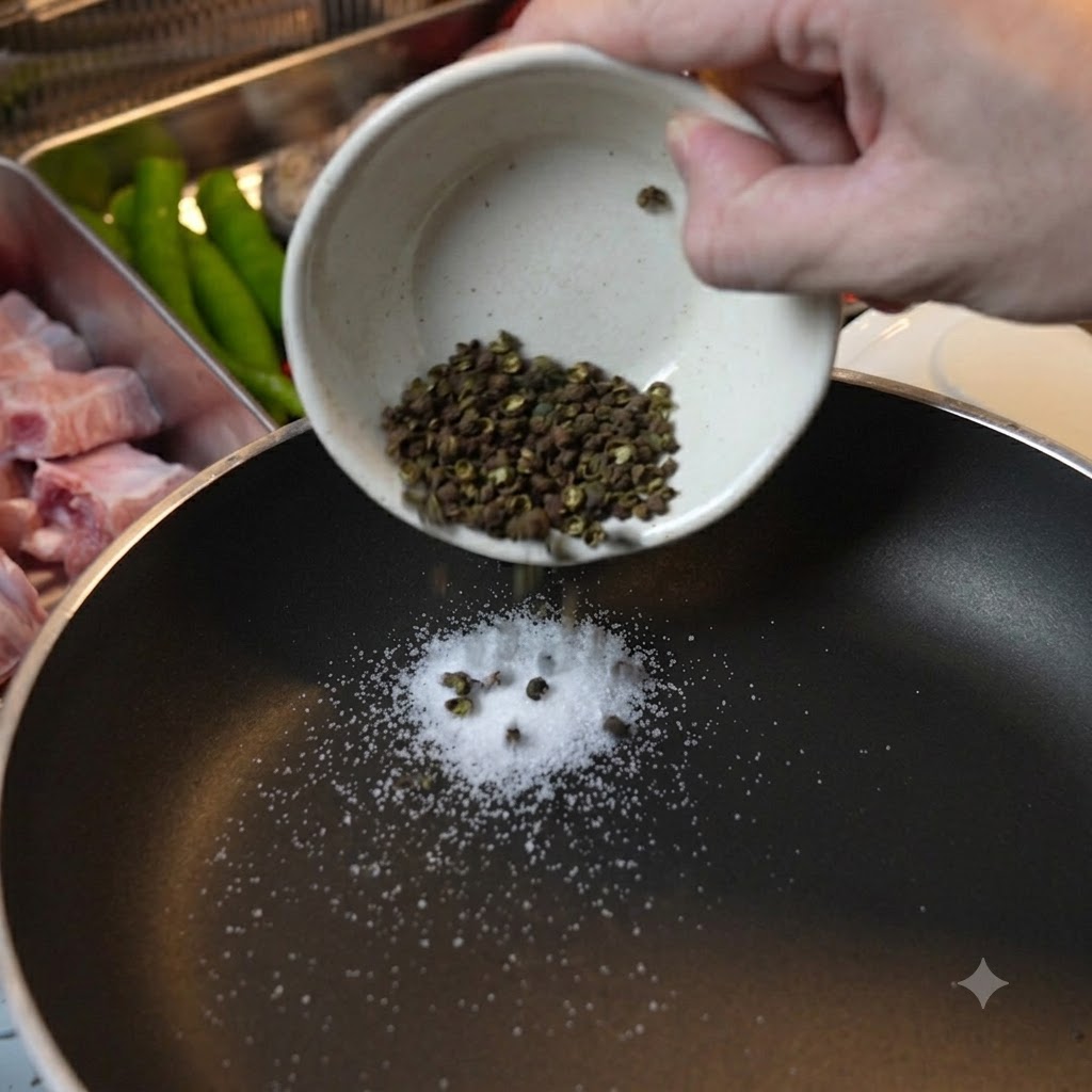 黒いフライパンに入れられ、乾煎りされる青花椒と粗塩。