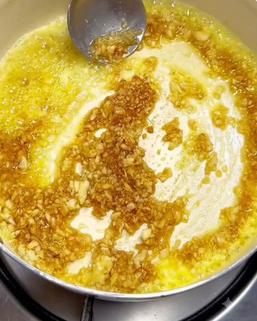 金属製のお玉を使い、フライパンの中で溶かしたバターに残りのみじん切りニンニクとソースの材料を混ぜ合わせている様子。