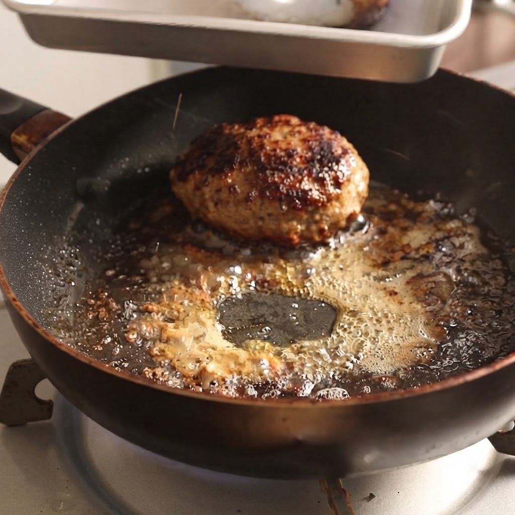 トングを使って、熱いフライパンからハンバーグのパティを持ち上げているところ。