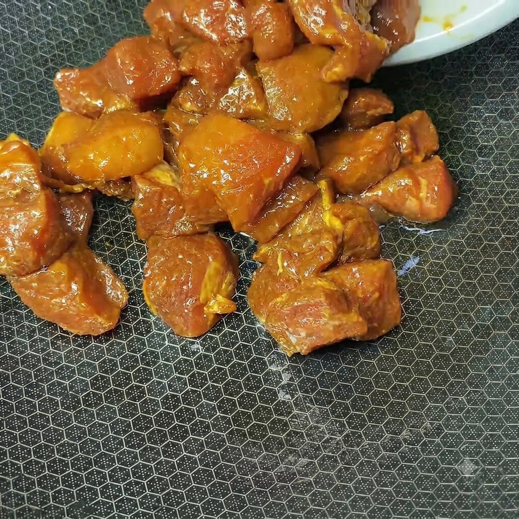 熱した中華鍋の中で赤褐色に下味づけされた豚肉が炒められている様子