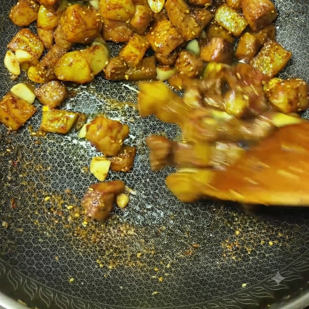 スパイスと調味料がしっかり絡み、中華鍋の中で激しく炒められている肉とポテトのキューブ