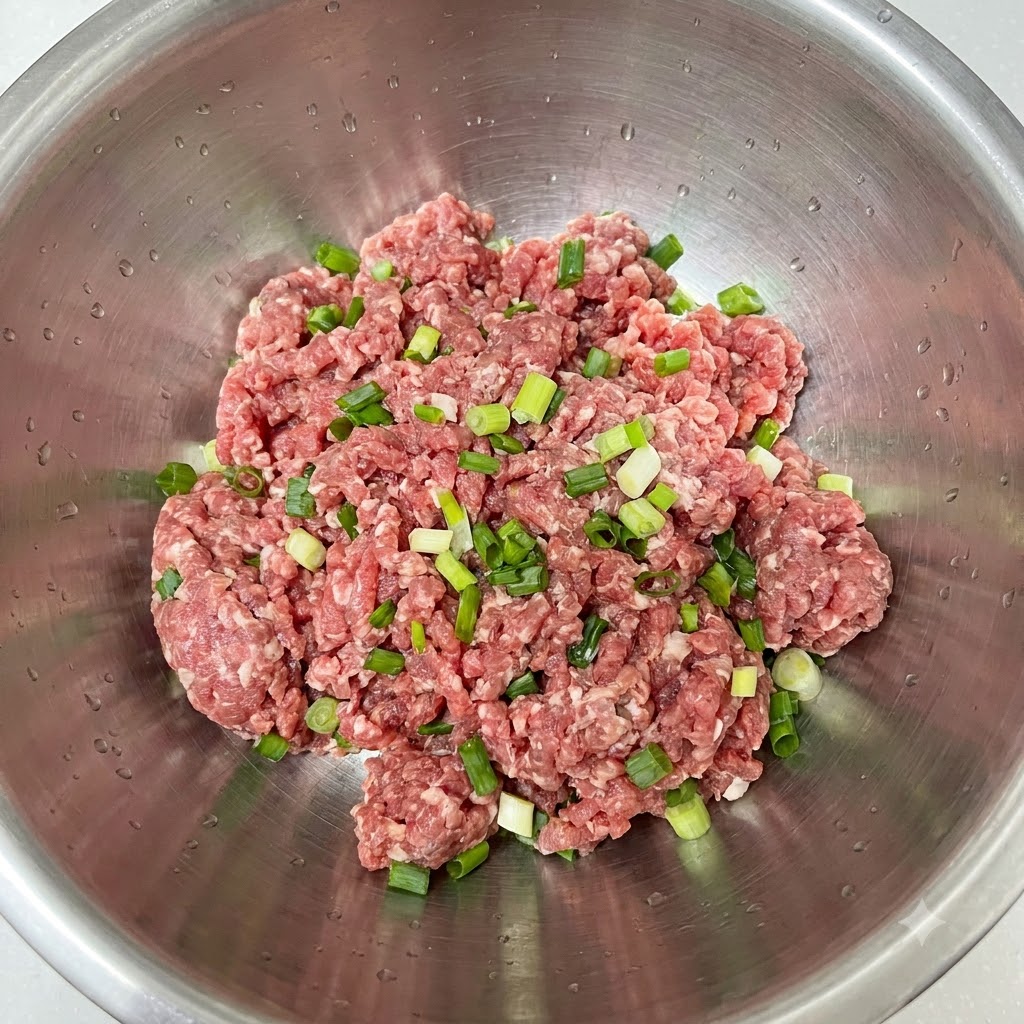 ボウルに入ったひき肉の上に刻みねぎが乗っている様子