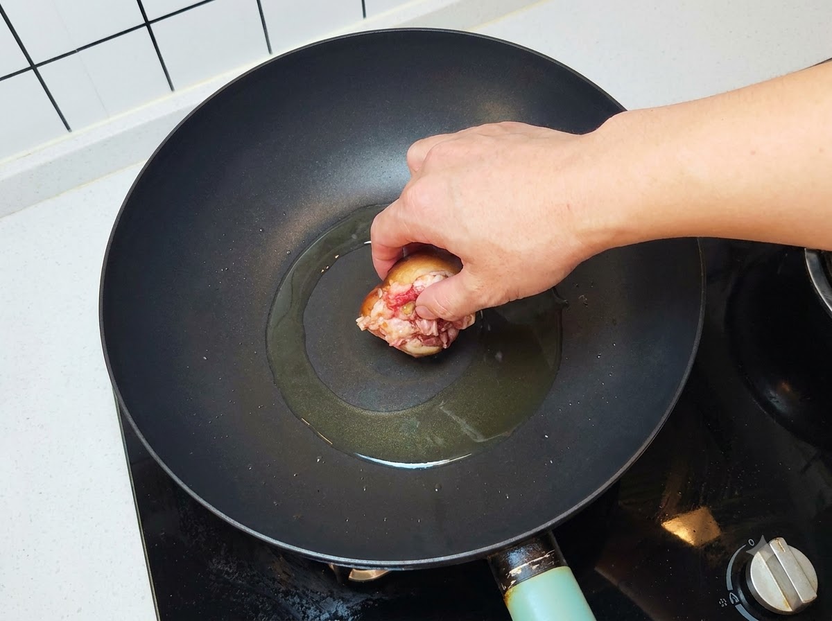 熱したフライパンに肉ダネを下にしてしいたけを置いている様子