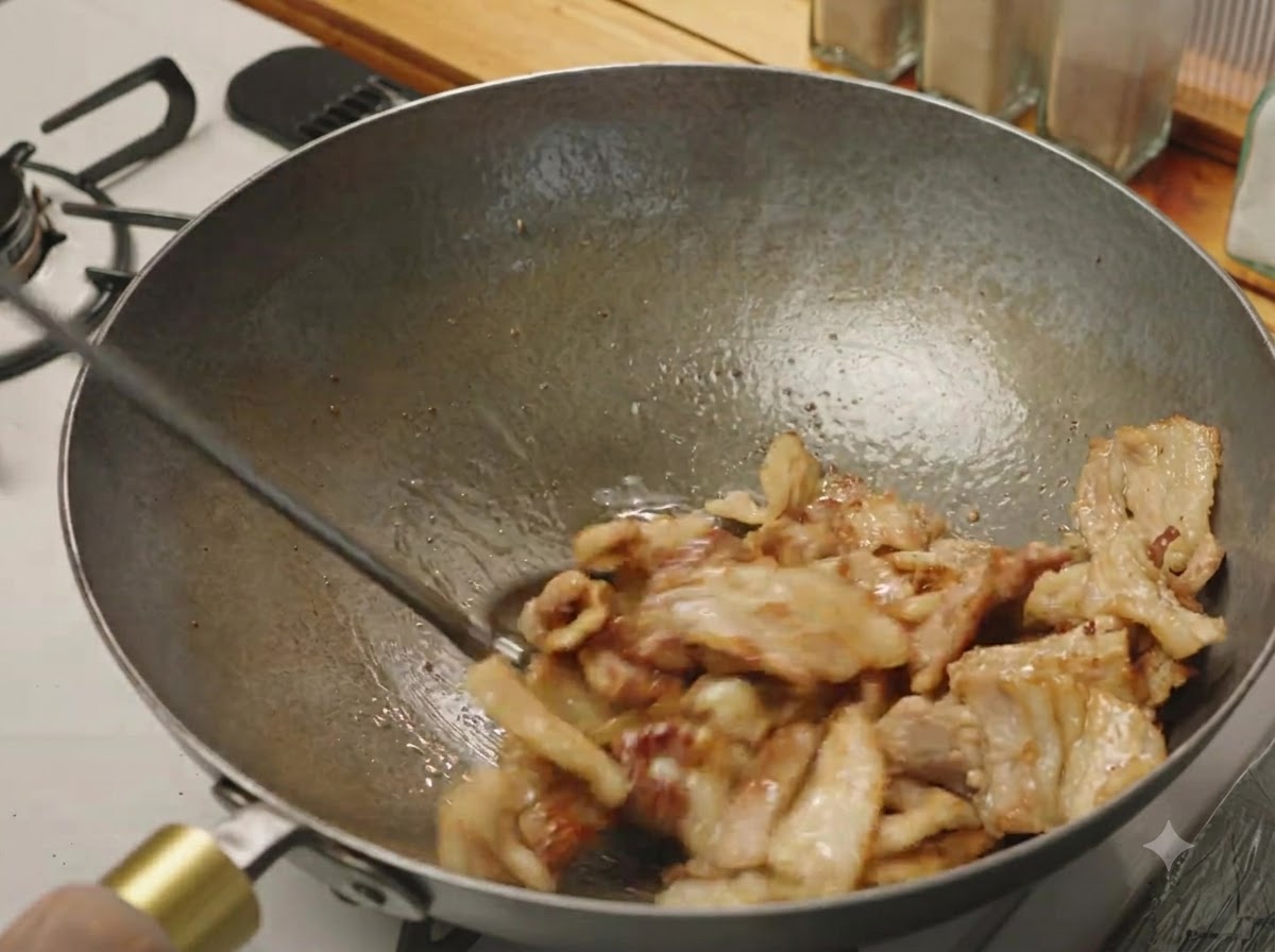 中華鍋の中で豚バラ肉のスライスが軽くきつね色に色づき、ジューシーに炒められている様子。