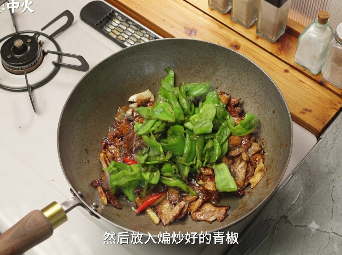 味付けされた豚肉が入った中華鍋に、緑のピーマンとキノコが加えられている様子。