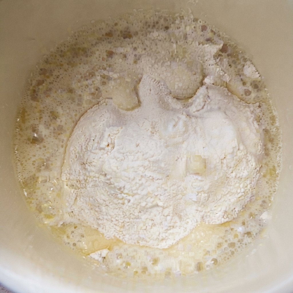 容器に入った小麦粉と塩の混合物に、熱した油を注いでいる様子。