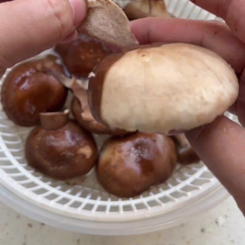 ザルの上で、手で生椎茸の外皮を剥いている様子。